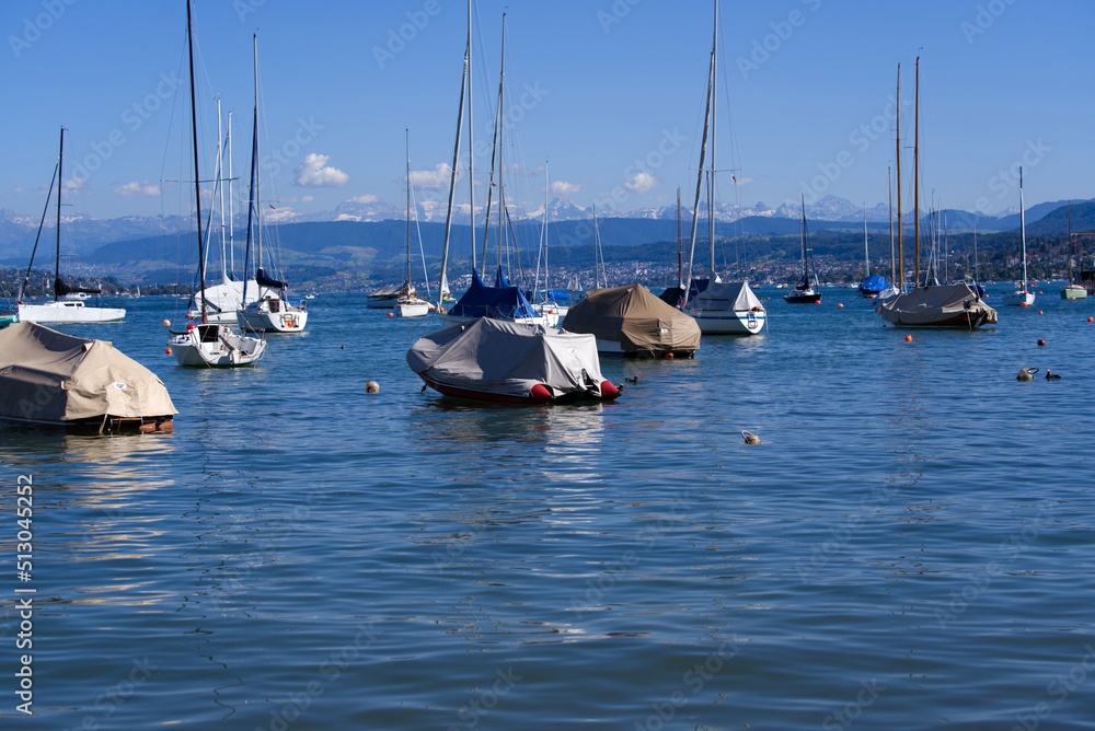 Obraz premium Scenic landscape with moored sailing boats at lakeshore of Lake Zürich at City of Zürich on a sunny summer day. Photo taken June 11th, 2022, Zurich, Switzerland.