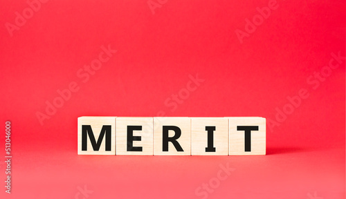 Merit symbol. Concept word Merit on wooden cubes. Beautiful red background. Business and Merit concept. Copy space.