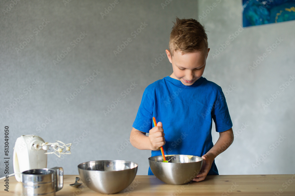 A child prepares dough in metal bowls. mix the ingredients A child prepares dough in metal bowls. mix the ingredients
