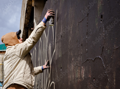 фотографія guy in a hood and black glasses writes graffiti