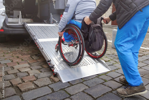 Obraz na płótnie Person on wheelchair with disability using accessible car ramp for transport with help of an assistant driver