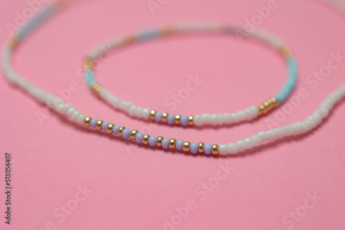 Luxury beaded bracelet and necklace on pink background with copy space.