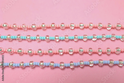 A set of beaded bracelets highlighted on a light pink background. Flat lying