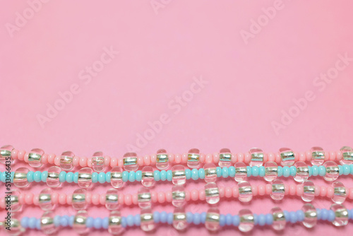 A set of beaded bracelets highlighted on a light pink background. Flat lying with copy space