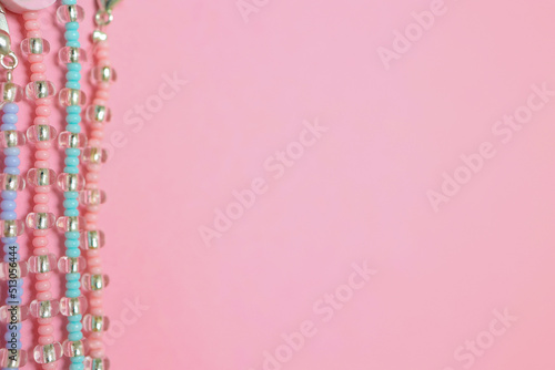 A set of beaded bracelets highlighted on a light pink background. Flat lying with copy space