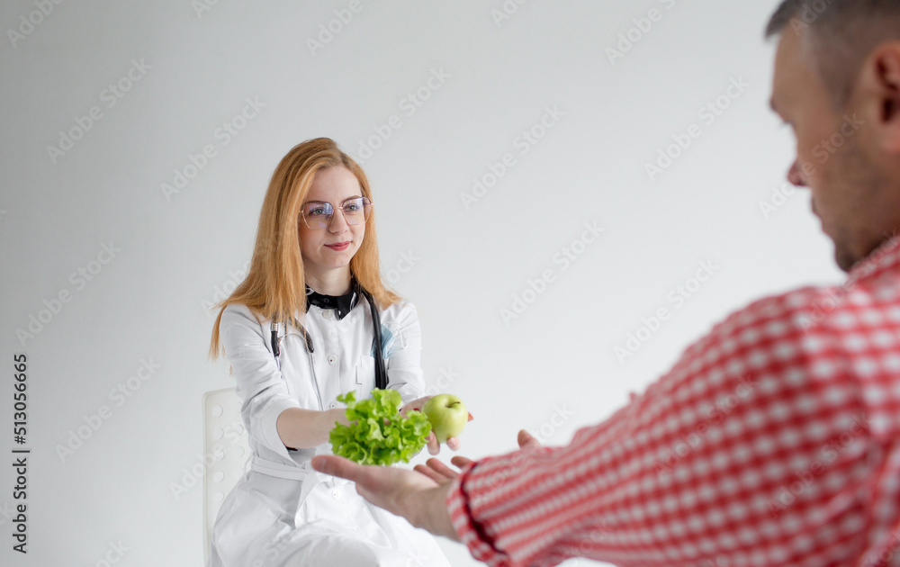 a female dietician holds out vegetables and fruits to a male patient. the concept of proper and healthy nutrition. a female dietician holds out vegetables and fruits to a male patient. the concept of proper and healthy nutrition.