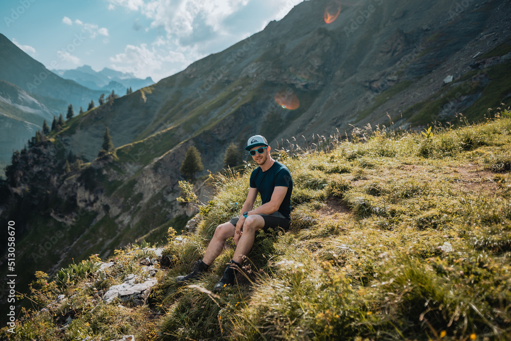 Obraz premium Un homme randonneur qui est en montagne lors d'une randonnée et qui regarde le magnifique panorama, avec un lac, des chemins et une forêt.