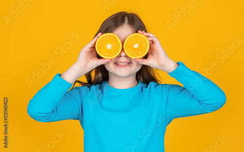 funny teen girl hold orange fruit on yellow background © be free