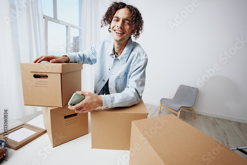 A young man cardboard boxes in the room unpacking with phone interior © SHOTPRIME STUDIO