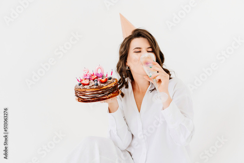 a happy lonely woman with a glass of champagne and a birthday cake with candles.