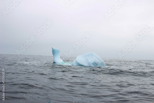 Wave crashing against small iceberg bit floating in sea