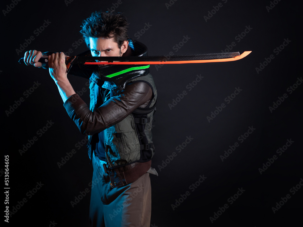 A guy in a cyberpunk image. Cyborg samurai is preparing to attack using a tuned sword. A young man in neon lighting on a black background A guy in a cyberpunk image. Cyborg samurai is preparing to attack using a tuned sword. A young man in neon lighting on a black background
