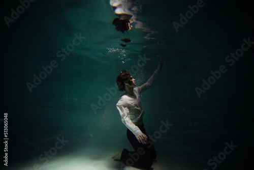 Wallpaper Mural Beautiful underwater shooting, guy in white shirt and pants has fallen under the water and is drowning. a young man relaxes down under surface of the water, waves and refraction of light under water Torontodigital.ca