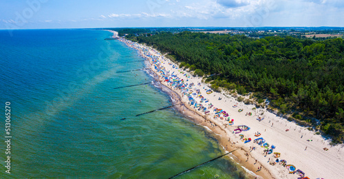 Wybrzeże morza bałtyckiego i piaszczysta plaża z opalającymi i kąpiącymi się plażowiczami w miejscowości Sarbinowo, widok z lotu ptaka