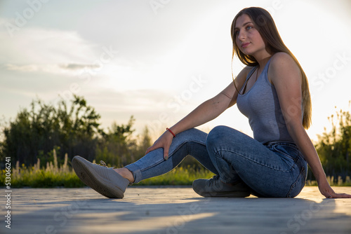 The girl in jeans sits on a tile floor.