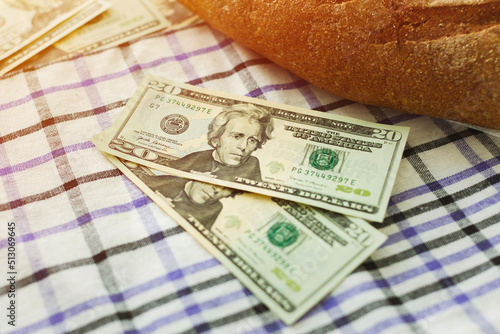 Two 20 dollars bills next to fresh bread on the table. World food crisis concept.