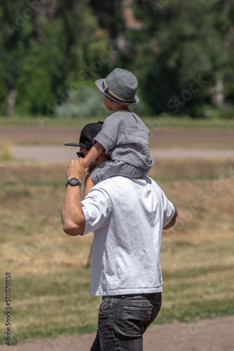 Exemplary dad. Son in father's arms. Father and son. Carry on the shoulders. Be a good father. Father's Day. Walking with a child. The role of men in raising a child.