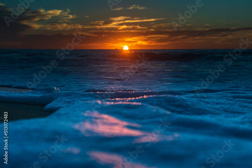 Sol poniendose sobre le mar, olas llegando a la arena.  photo