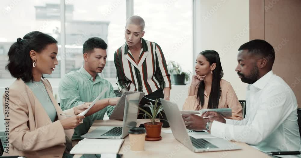 Group of businesspeople in meeting going through documents at work. Confident female businesswoman discussing ideas with her colleagues in a boardroom. Business professionals reading reports together
