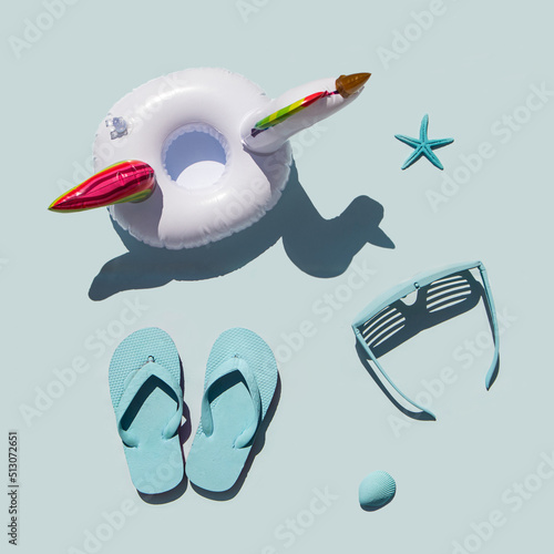 Minimalistic beach concept. Sea symbols idea. Sunglasses, flip flops, starfishes and seashell on pastel blue background. Creative summer concept. Holiday composition. Flat lay.