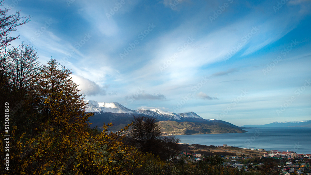 Beagle Channel seen from a forest path with native vegetation in autumn and its snowy mountains in the background. Ushuaia, Argentina