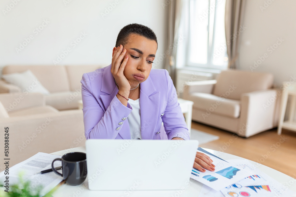 Frustrated young African American businesswoman working on a laptop sitting at desk in office. Frustrated young African American businesswoman working on a laptop sitting at desk in office.