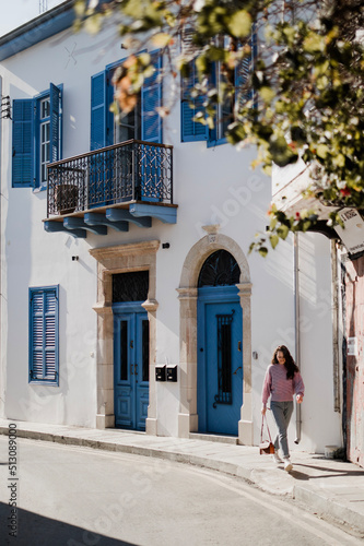 Woman is walking near beautiful building with blue doors and windows in Cyprus © Yurii Kushniruk