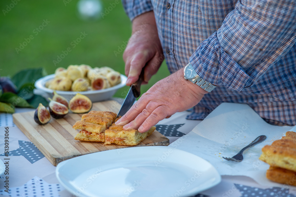 Elderly man spread fig jam on slices of bread outdoor.