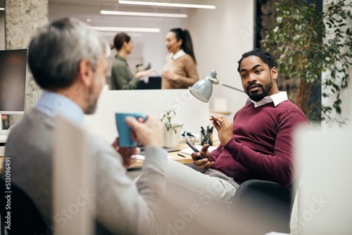 Black businessman talking to his colleague in office.