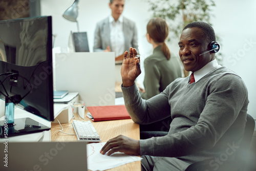 Black businessman talking while having conference call via desktop PC in office. photo