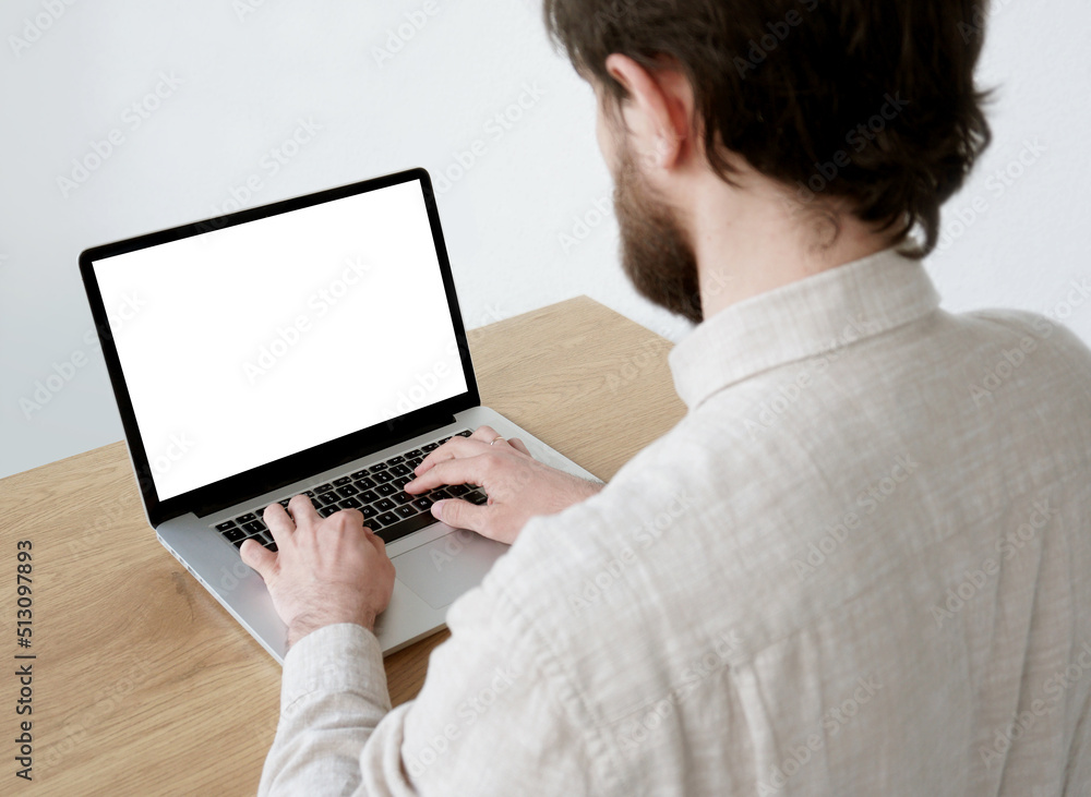 Young man in office using laptop. Businessman, blogger, student freelancer working on computer. Laptop mock up. Business and technology concept Young man in office using laptop. Businessman, blogger, student freelancer working on computer. Laptop mock up. Business and technology concept