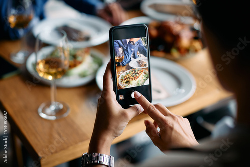 Close up of businesswoman photographing her food during lunch in restaurant.