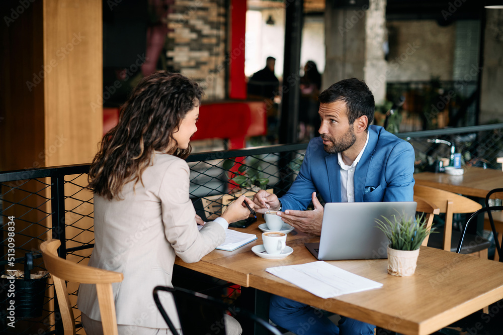 Businessman talking to female colleague and drinking coffee during meeting in cafe. Businessman talking to female colleague and drinking coffee during meeting in cafe.
