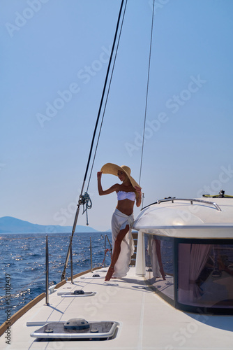 Beautiful young blond woman in bikini standing on catamaran at sunny summer day © Anatoly Repin