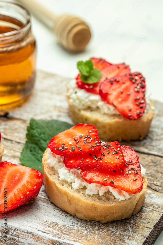 Sandwich with strawberries, ricotta cheese, mint and honey on wooden board. vertical image. top view. place for text Sandwich with strawberries, ricotta cheese, mint and honey on wooden board. vertical image. top view. place for text