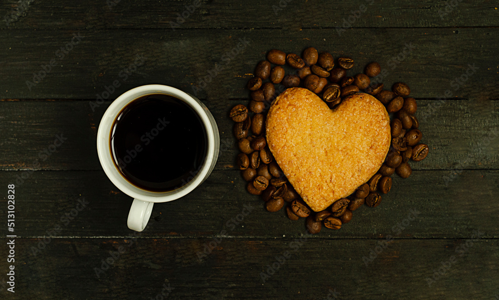 A cup of coffee and love cookie with coffee beans on wooden surface,top view.Valentine day holiday.