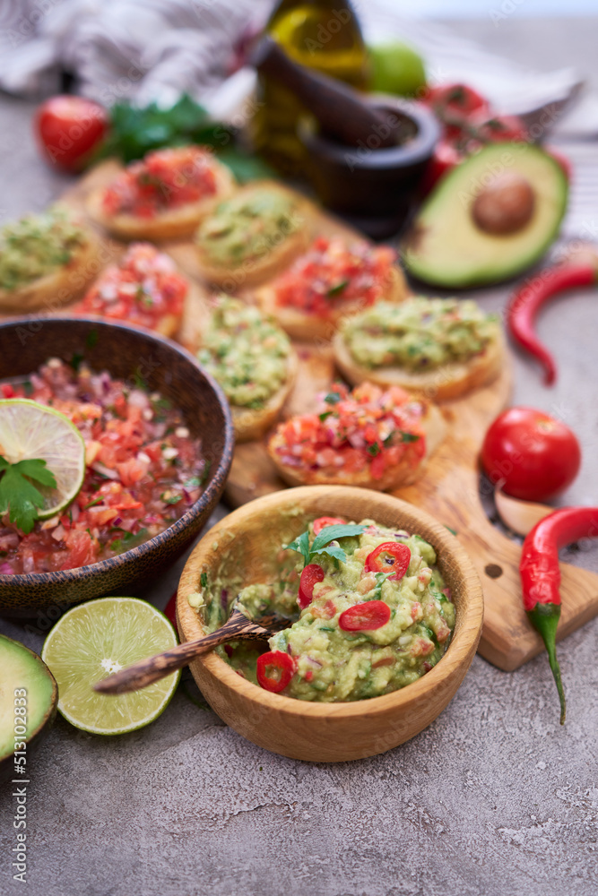 tasty salsa and guacamole bruschetta snacks at domestic kitchen on wooden cutting board