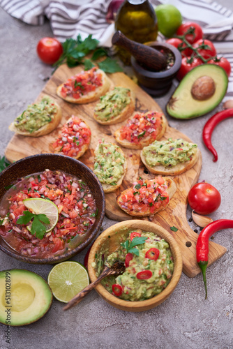 tasty salsa and guacamole bruschetta snacks at domestic kitchen on wooden cutting board