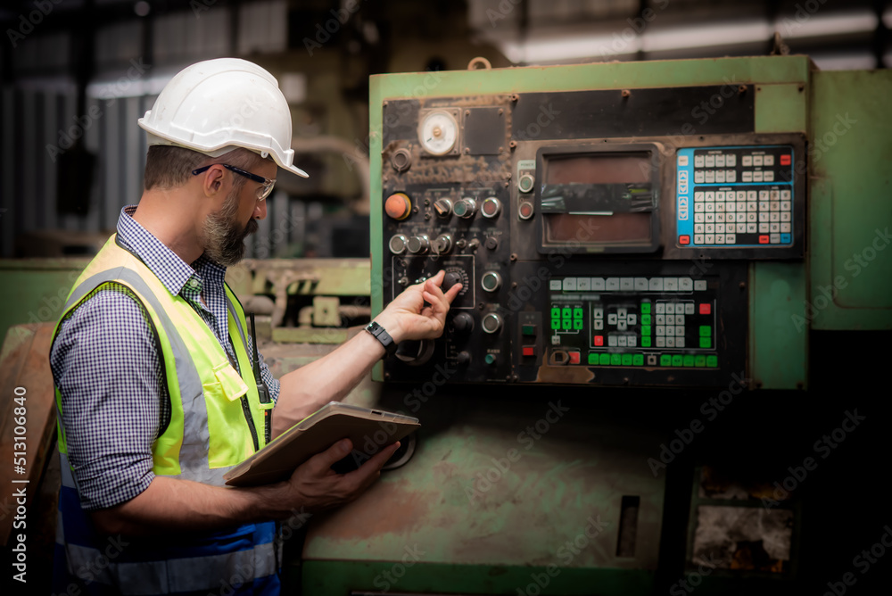 Caucasian male engineer or technician in safety uniform Working and checking machinery operation to maintenance information with online production data of the machinery in the tablet. Caucasian male engineer or technician in safety uniform Working and checking machinery operation to maintenance information with online production data of the machinery in the tablet.