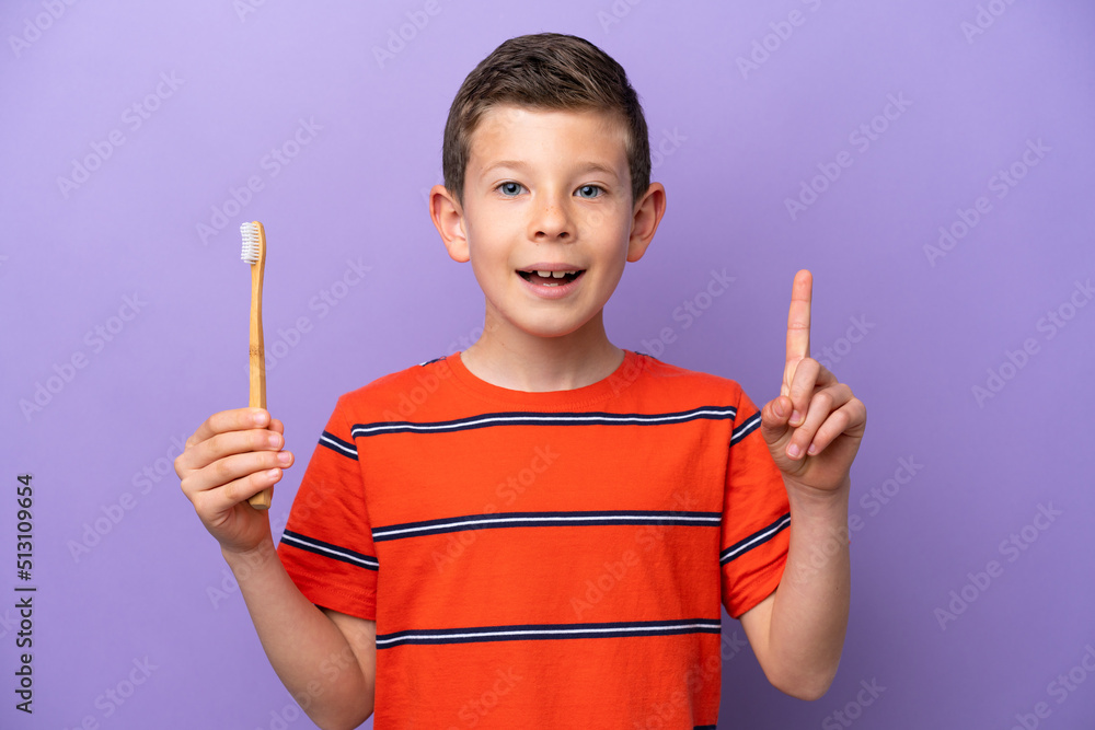 Little boy brushing teeth isolated on purple background pointing up a great idea Little boy brushing teeth isolated on purple background pointing up a great idea
