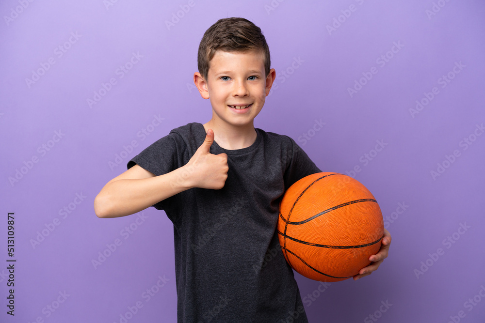 Little boy playing basketball isolated on purple background giving a thumbs up gesture Little boy playing basketball isolated on purple background giving a thumbs up gesture