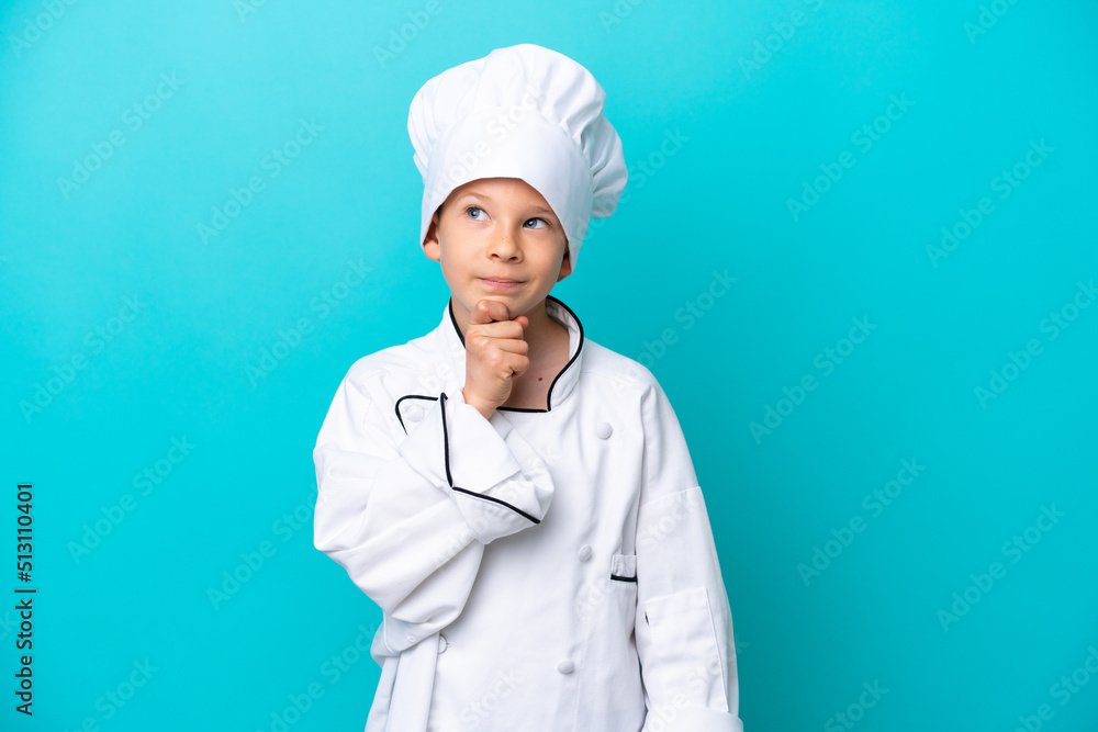 Little chef boy isolated on blue background and looking up Little chef boy isolated on blue background and looking up