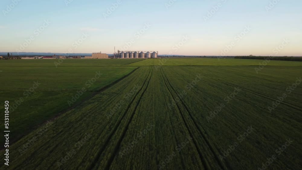 Grain elevator. Metal grain elevator in agricultural zone. Agriculture storage for harvest. Grain silos on green nature background. Exterior of agricultural factory. Nobody. Grain elevator. Metal grain elevator in agricultural zone. Agriculture storage for harvest. Grain silos on green nature background. Exterior of agricultural factory. Nobody.