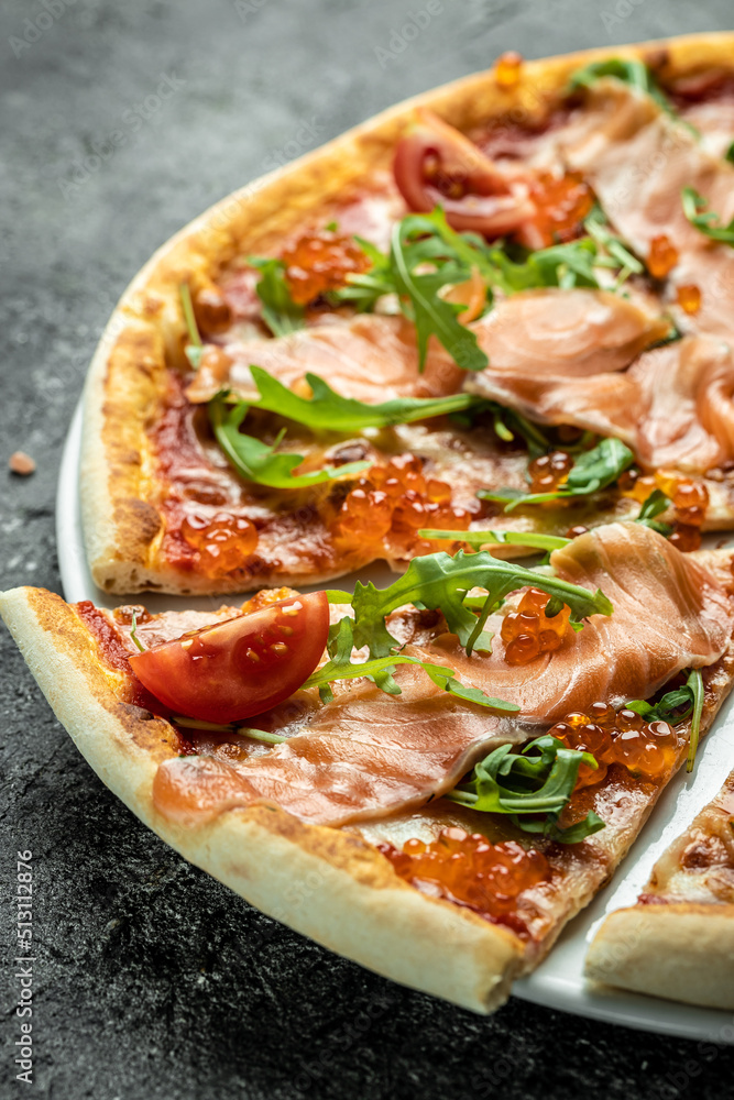 salmon Italian Pizza with red caviar, tomatoes and aragula ready to eat on a dark background. banner, menu, recipe place for text, top view salmon Italian Pizza with red caviar, tomatoes and aragula ready to eat on a dark background. banner, menu, recipe place for text, top view