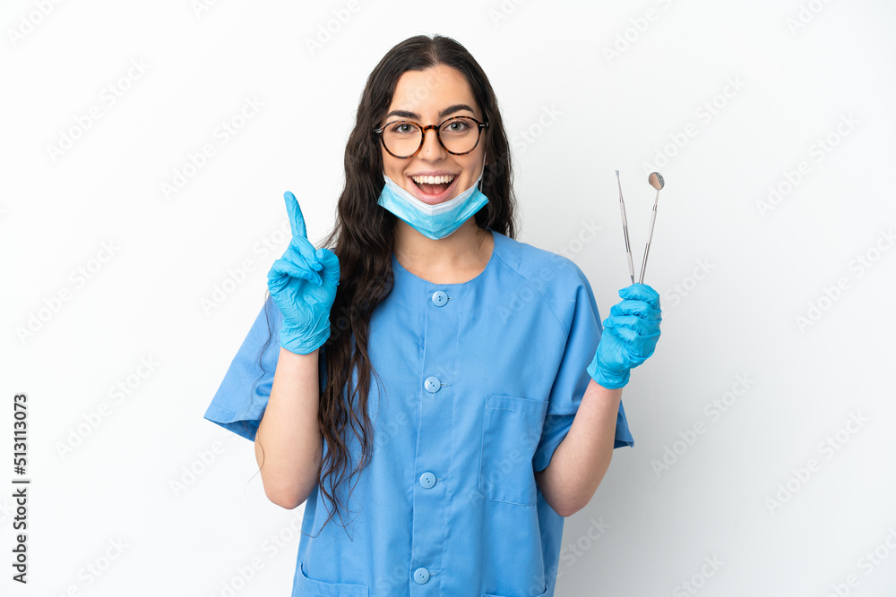 Young woman dentist holding tools isolated on white background thinking an idea pointing the finger up Young woman dentist holding tools isolated on white background thinking an idea pointing the finger up