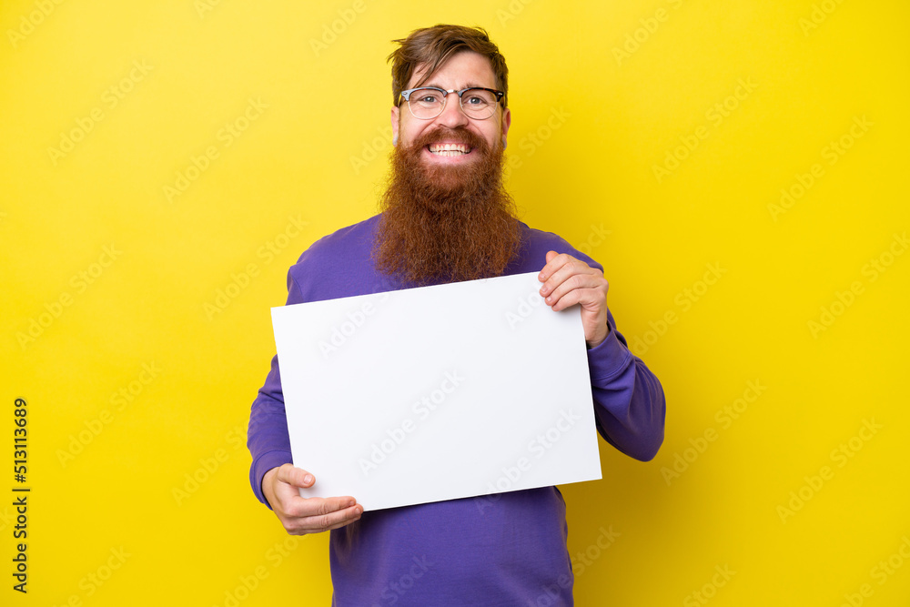Redhead man with beard isolated on yellow background holding an empty placard with happy expression Redhead man with beard isolated on yellow background holding an empty placard with happy expression