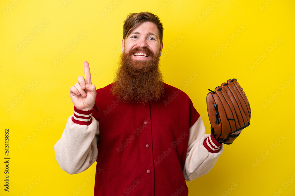 Redhead player man with beard with baseball glove isolated on yellow background showing and lifting a finger in sign of the best Redhead player man with beard with baseball glove isolated on yellow background showing and lifting a finger in sign of the best