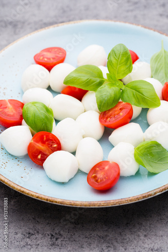 Delicious caprese salad with ripe cherry tomatoes and mini mozzarella cheese balls with fresh basil leaves.