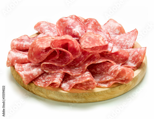 sliced salami over wooden round cutting board, isolated on white background
