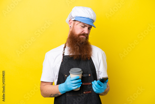 Fishmonger wearing an apron isolated on yellow background holding coffee to take away and a mobile